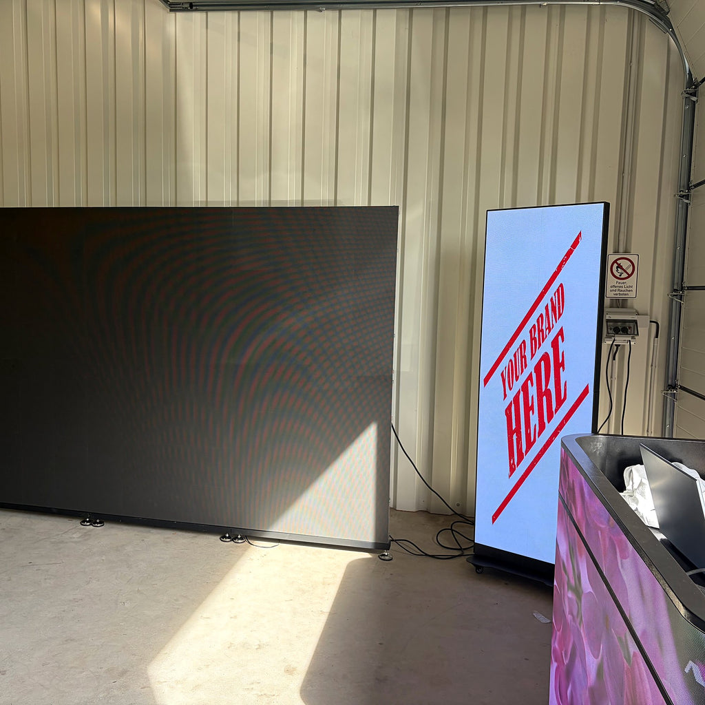 LED screen poster with placeholder ad text next to an unlit LED wall in a workshop hall