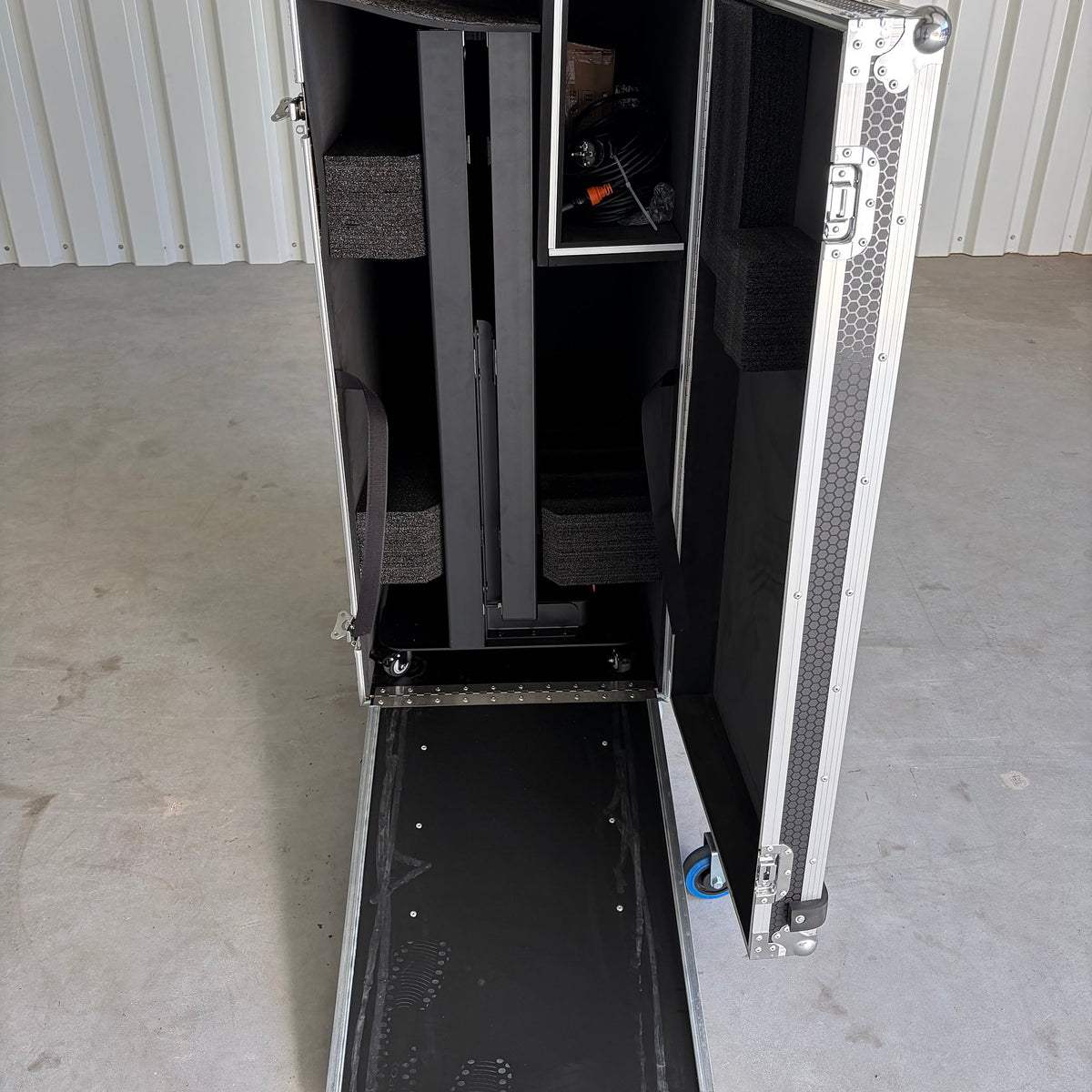 Open flight case with a fold-out ramp and the packed poster